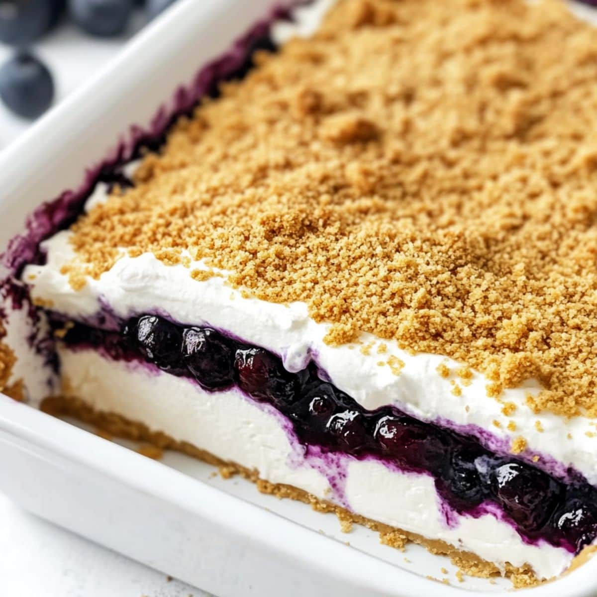 Blueberry yum yum in a baking dish with a slice removed to show the layers.