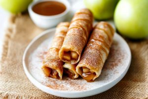 Caramel apple taquitos served with a dipping sauce.