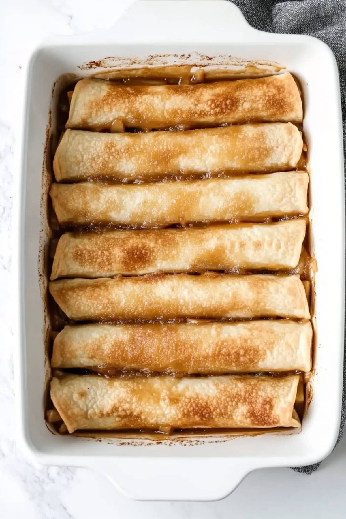 Caramel apple taquitos in a 9x13 white baking dish.