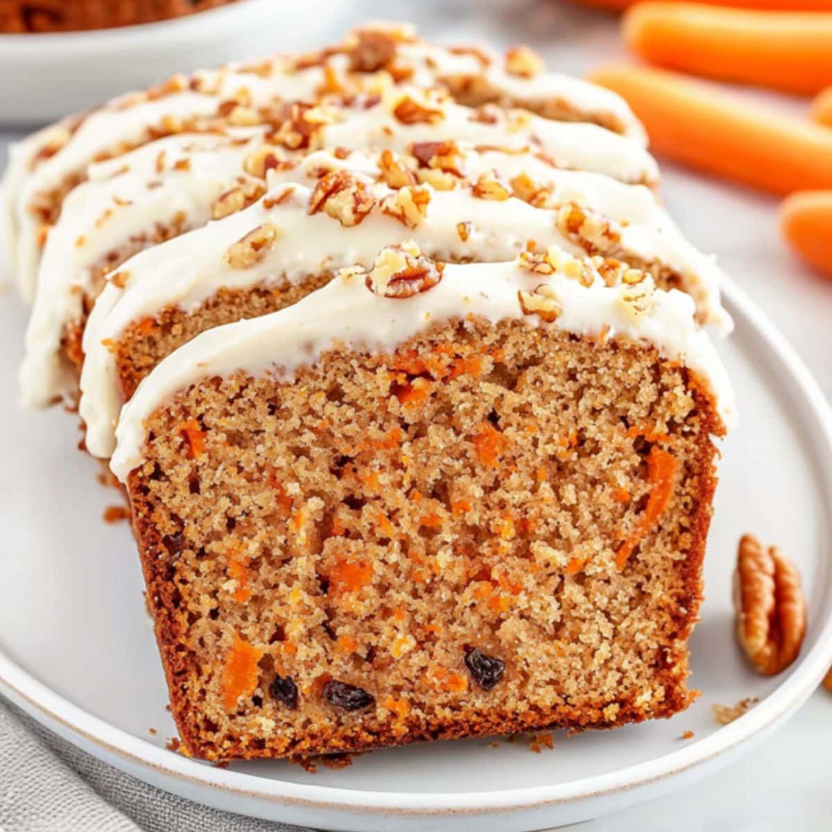 Carrot cake loaf bread slices with cream cheese frosting served in a white plate.