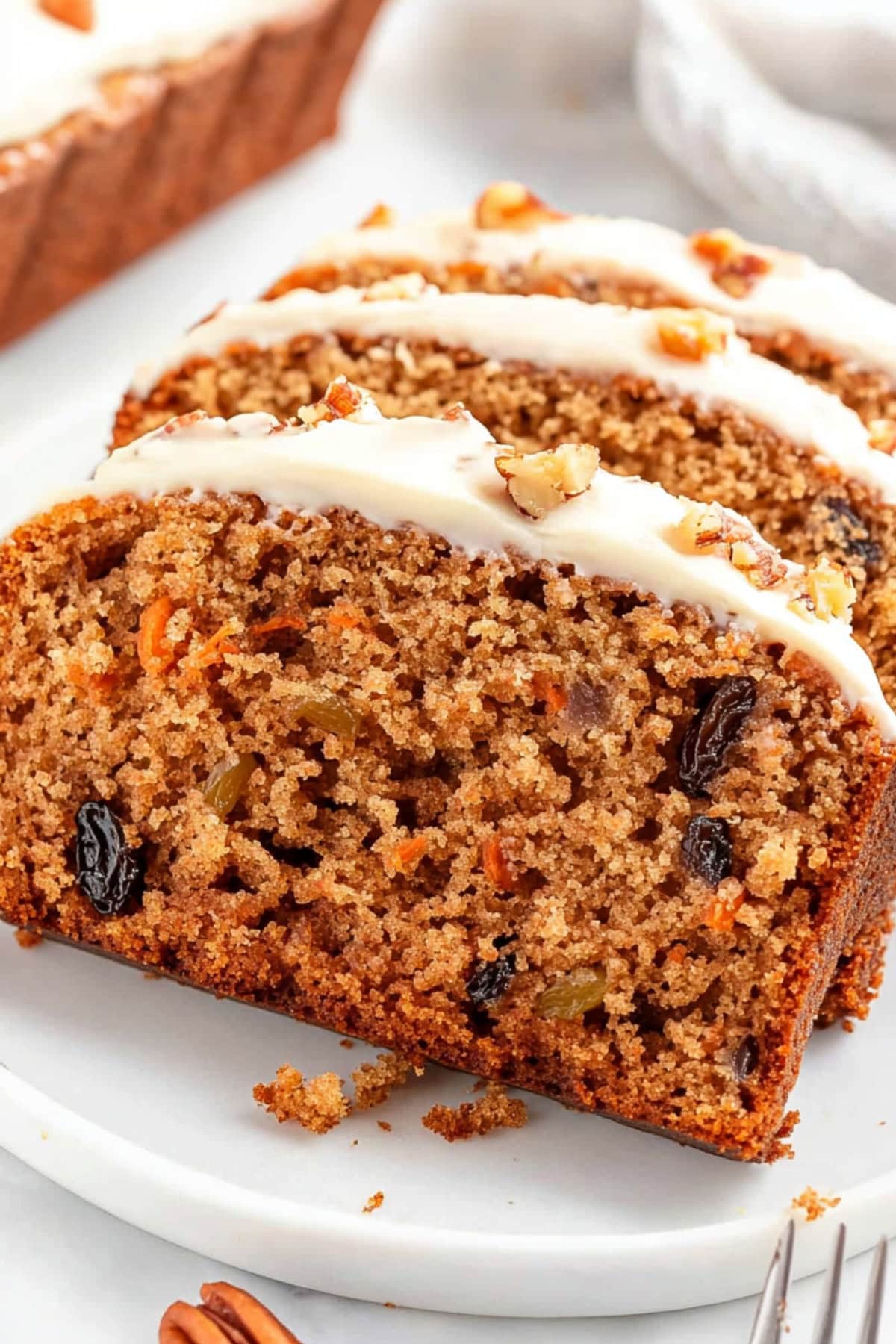 Slices of carrot cake bread with cream cheese served in a white plate.