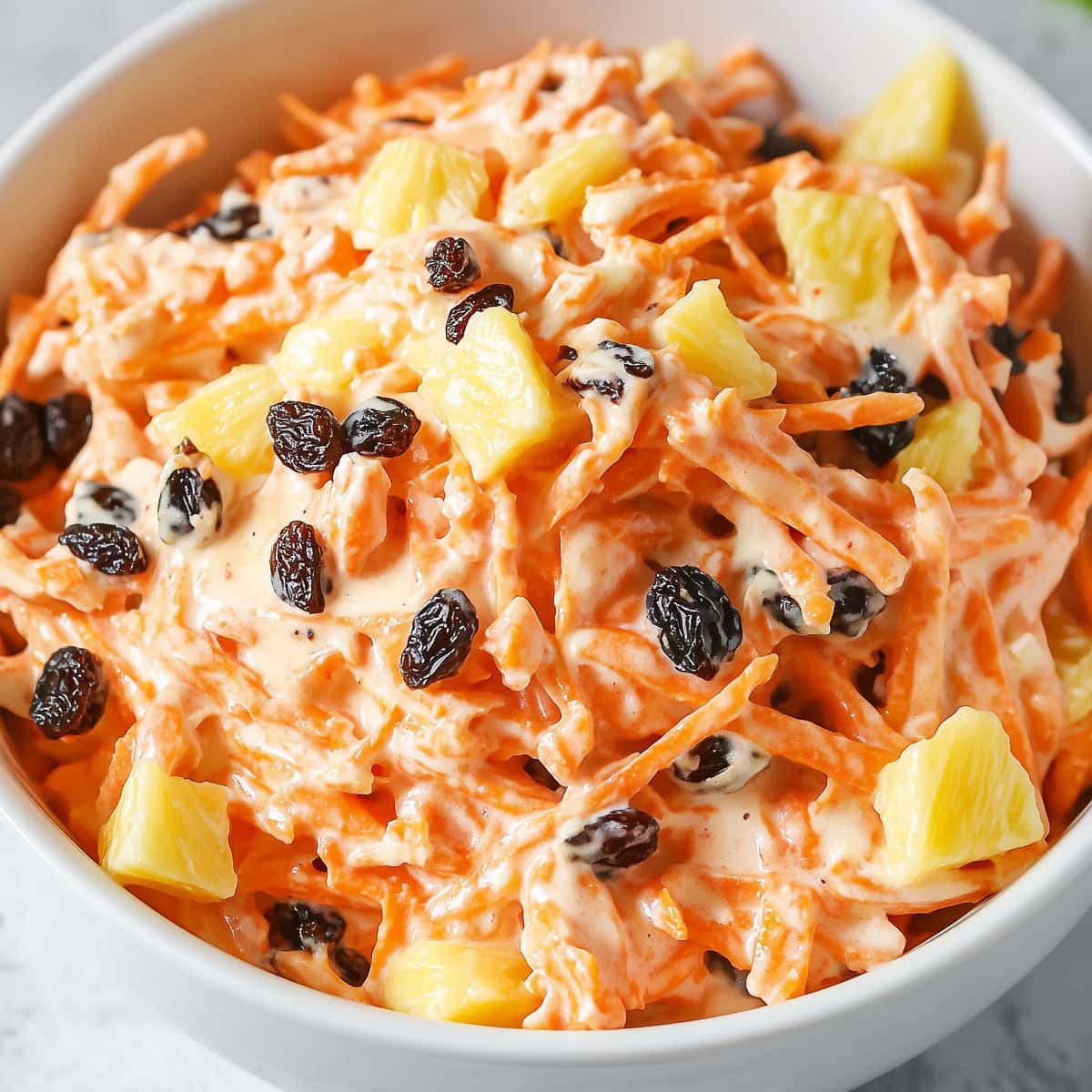 A large bowl of carrot raisin salad with mayo dressing.