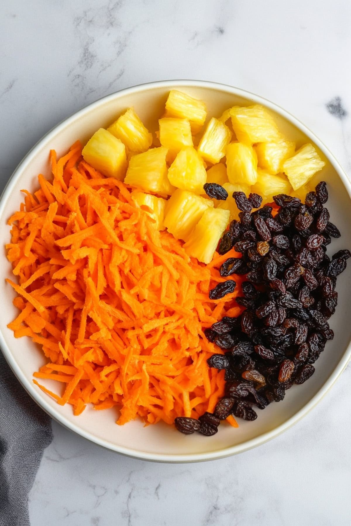 Shredded Carrots, Pineapple Bits, and Raisins in a Plate, Top View.