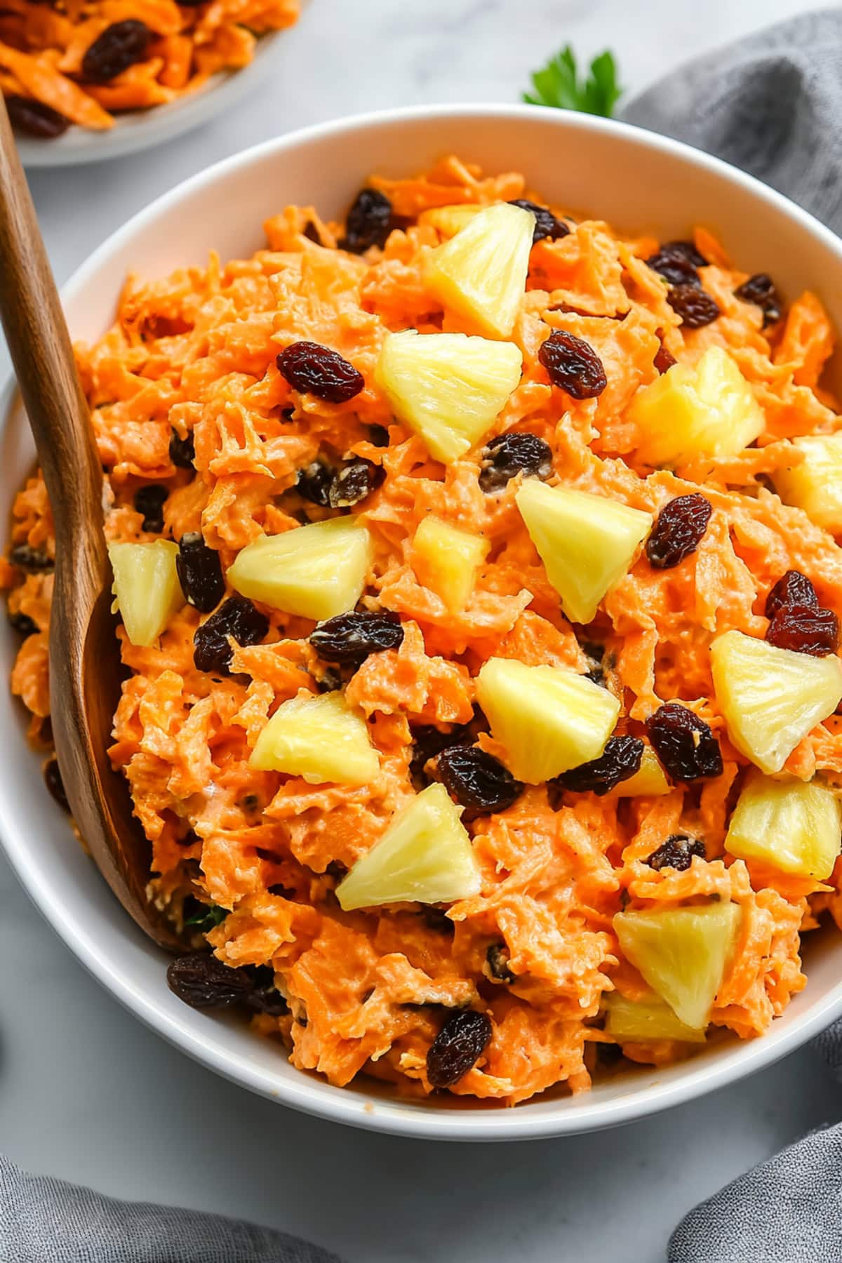 A vibrant carrot raisin salad with creamy dressing in a bowl.