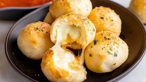 Cheese bombs with herbs in a brown plate, served with marinara sauce.