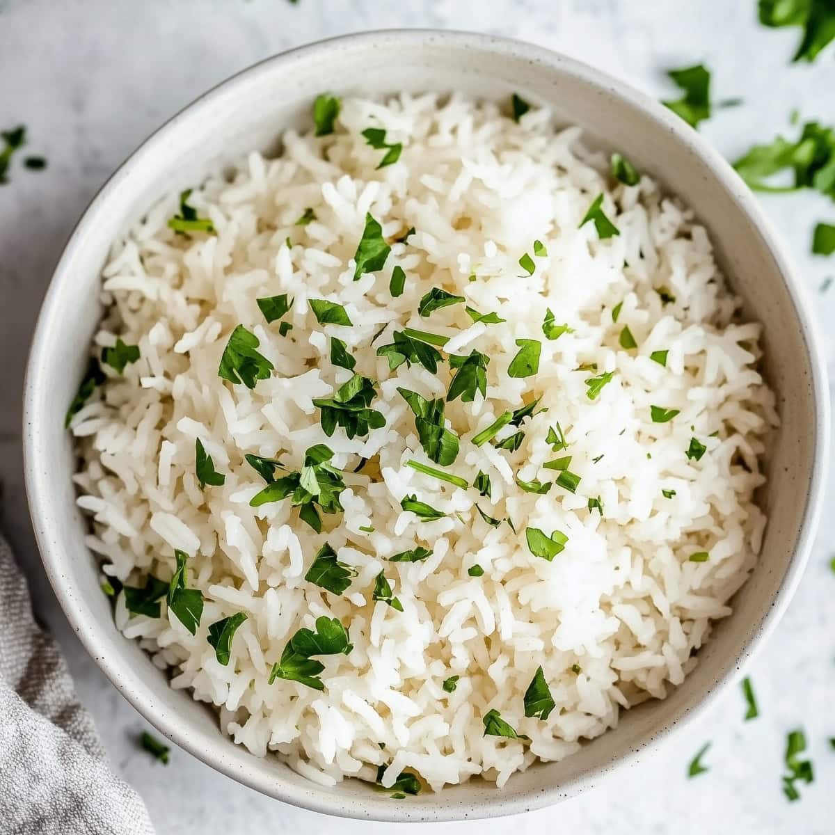 An overhead view of a bowl of rich coconut rice with fresh herbs.