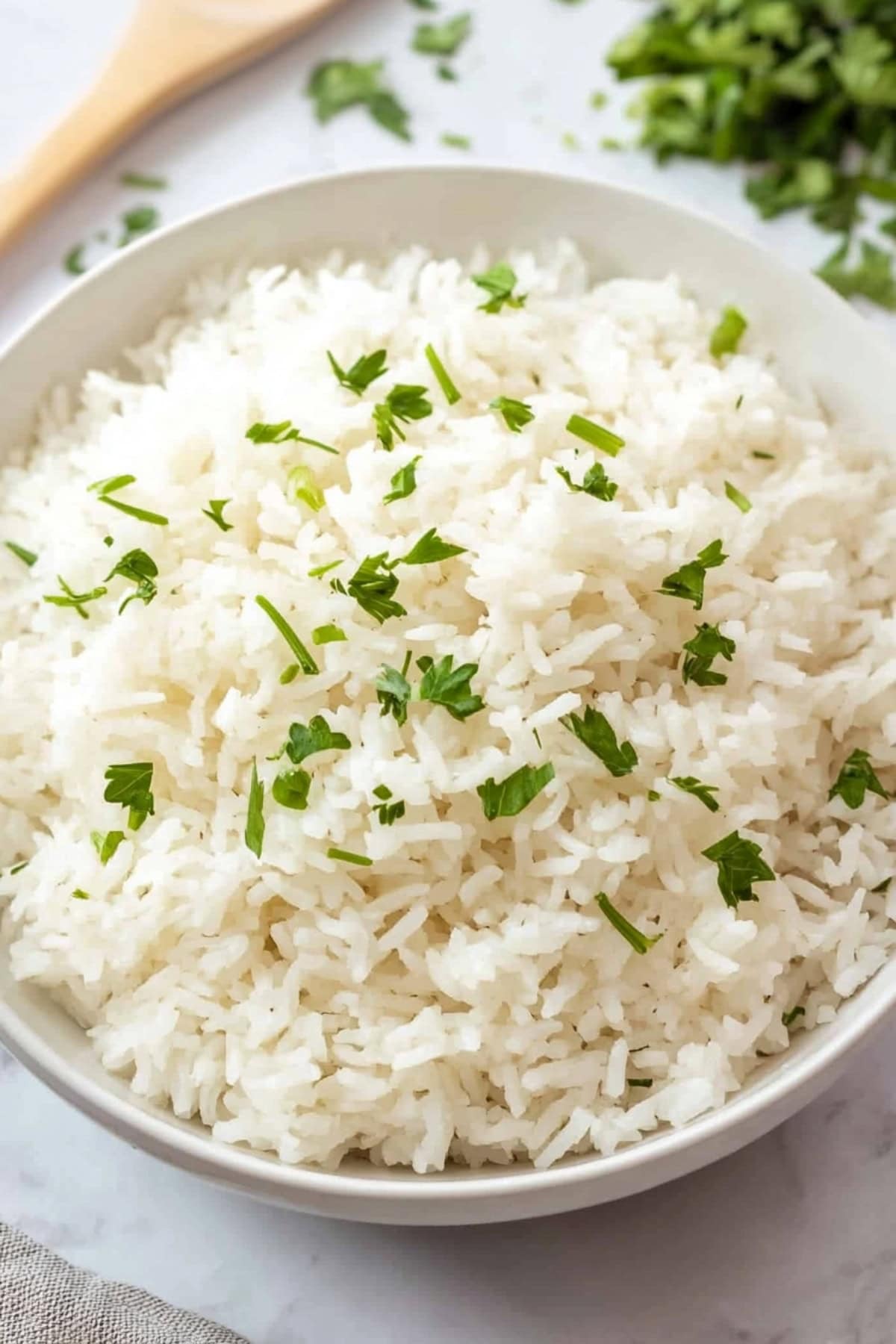 A bowl of coconut rice, garnished with fresh cilantro, close up.