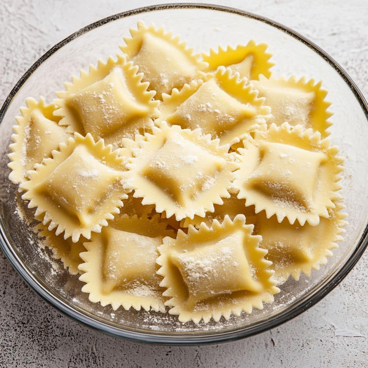 Raw ravioli pasta in a glass bowl.