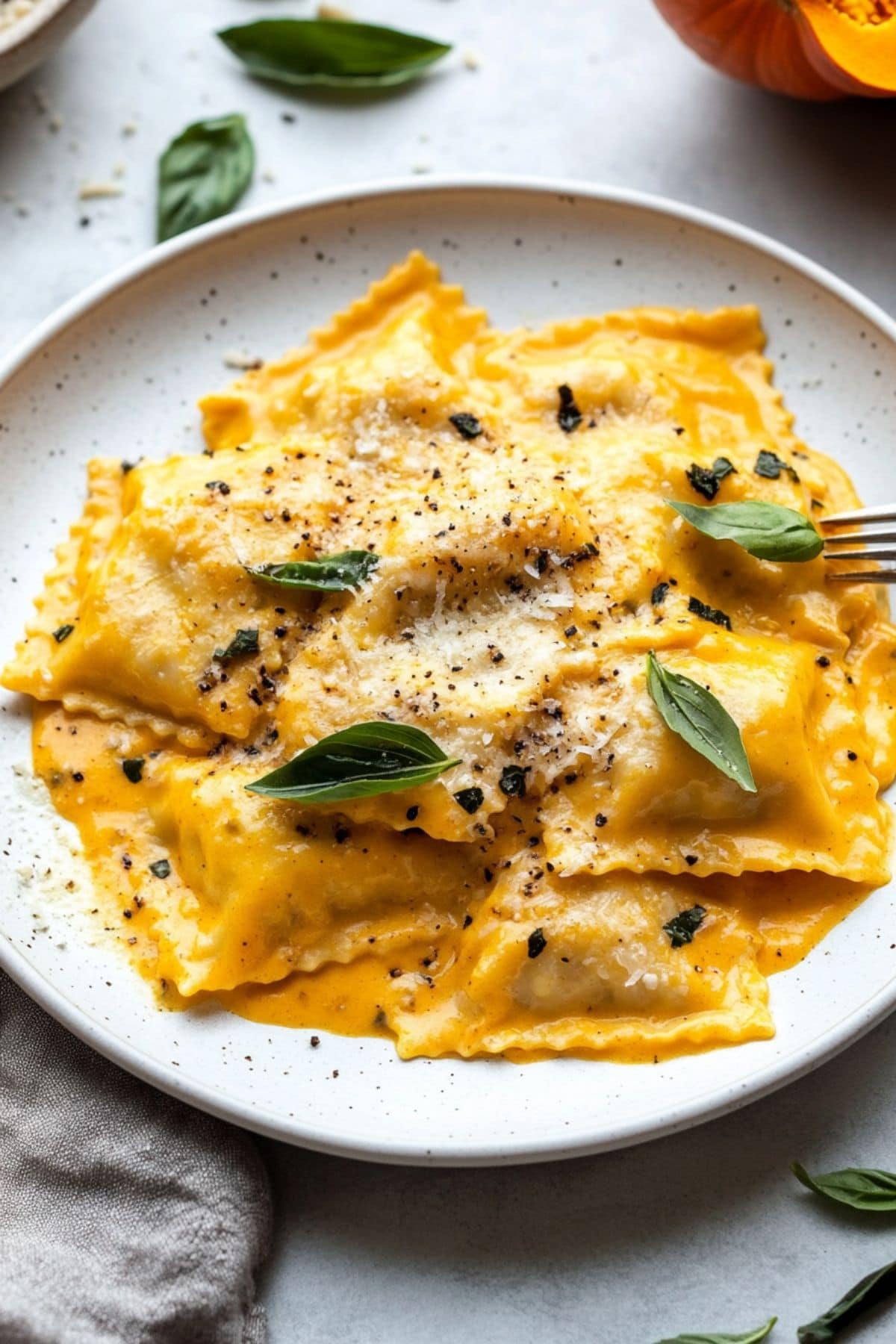 Cheesy and creamy ravioli with pumpkin sauce served in a white plate.