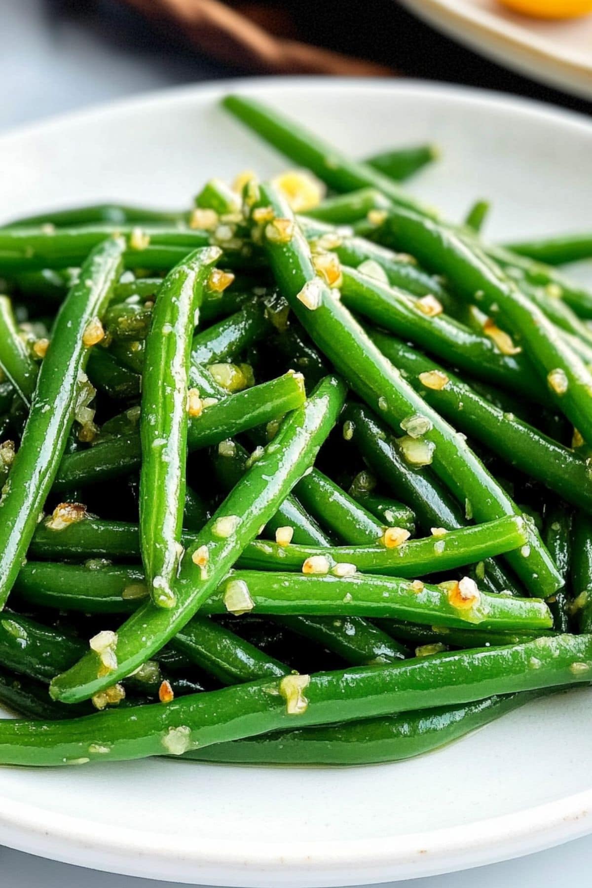 Green beans sauteed in butter and garlic served on a white plate.