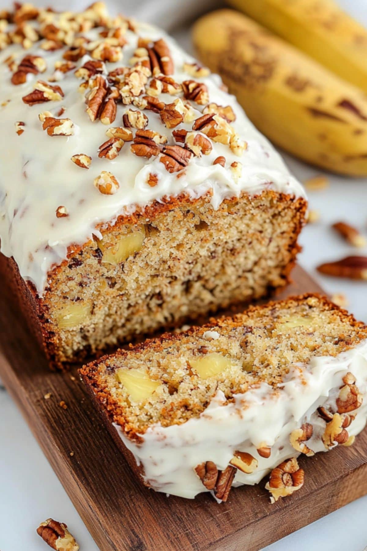 Sliced loaf bread with cream frosting garnished with chopped pecans.