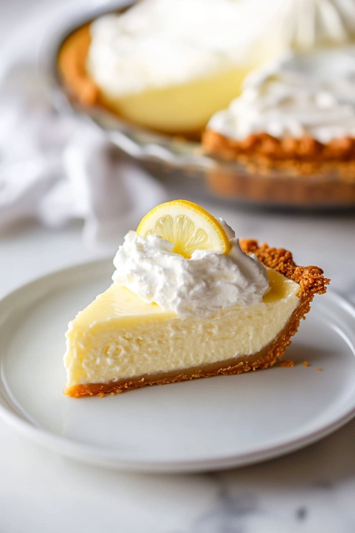 Sliced homemade lemon chiffon pie topped with whipped cream on a plate