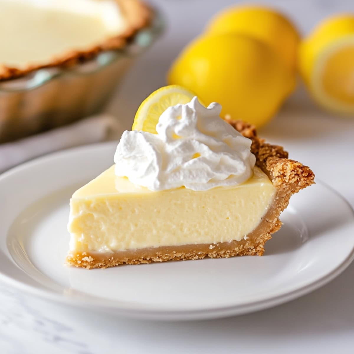 A slice of light and airy lemon chiffon pie topped with whipped cream, side view