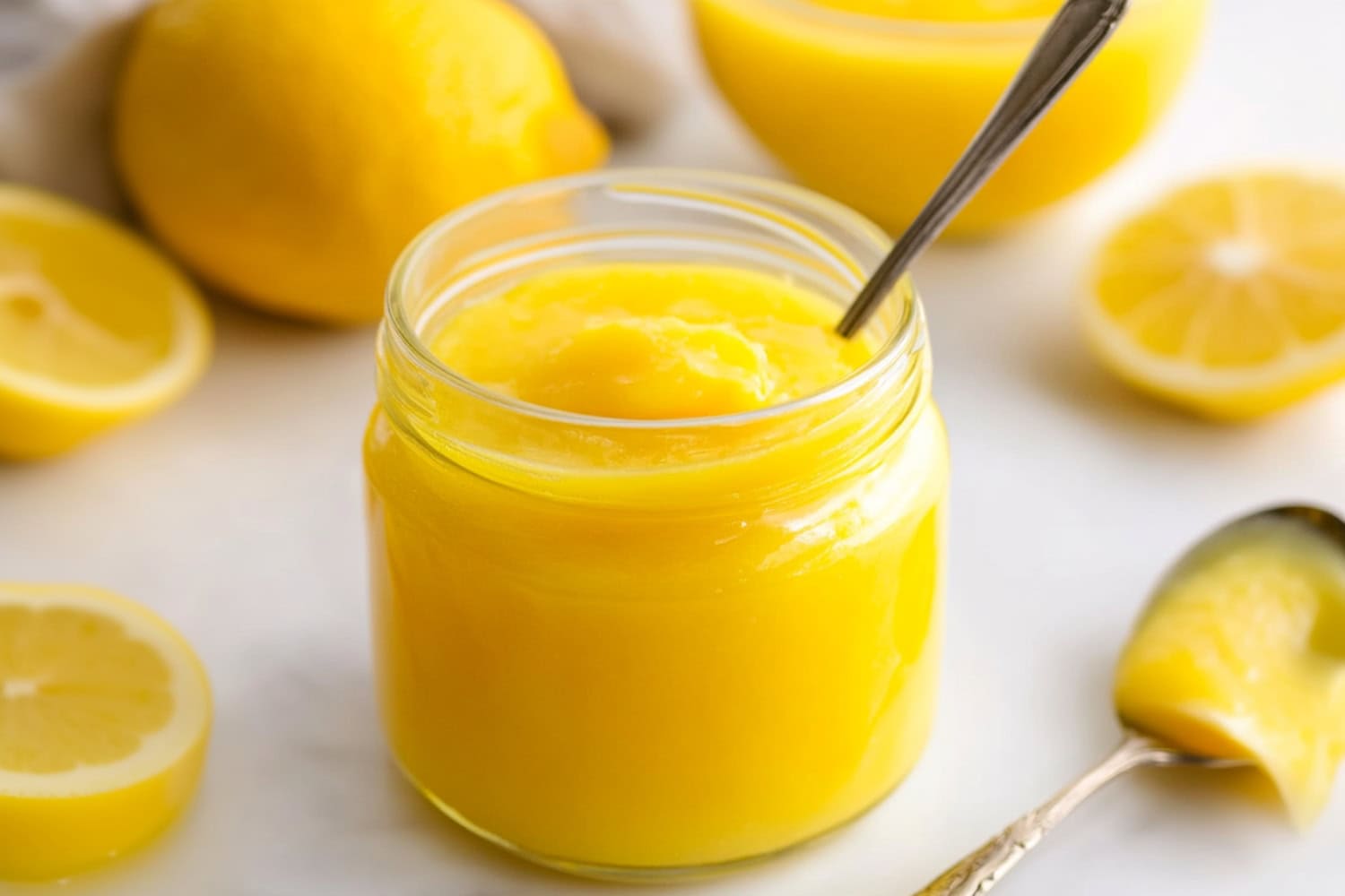 A jar of vibrant lemon curd surrounded by fresh fruits.