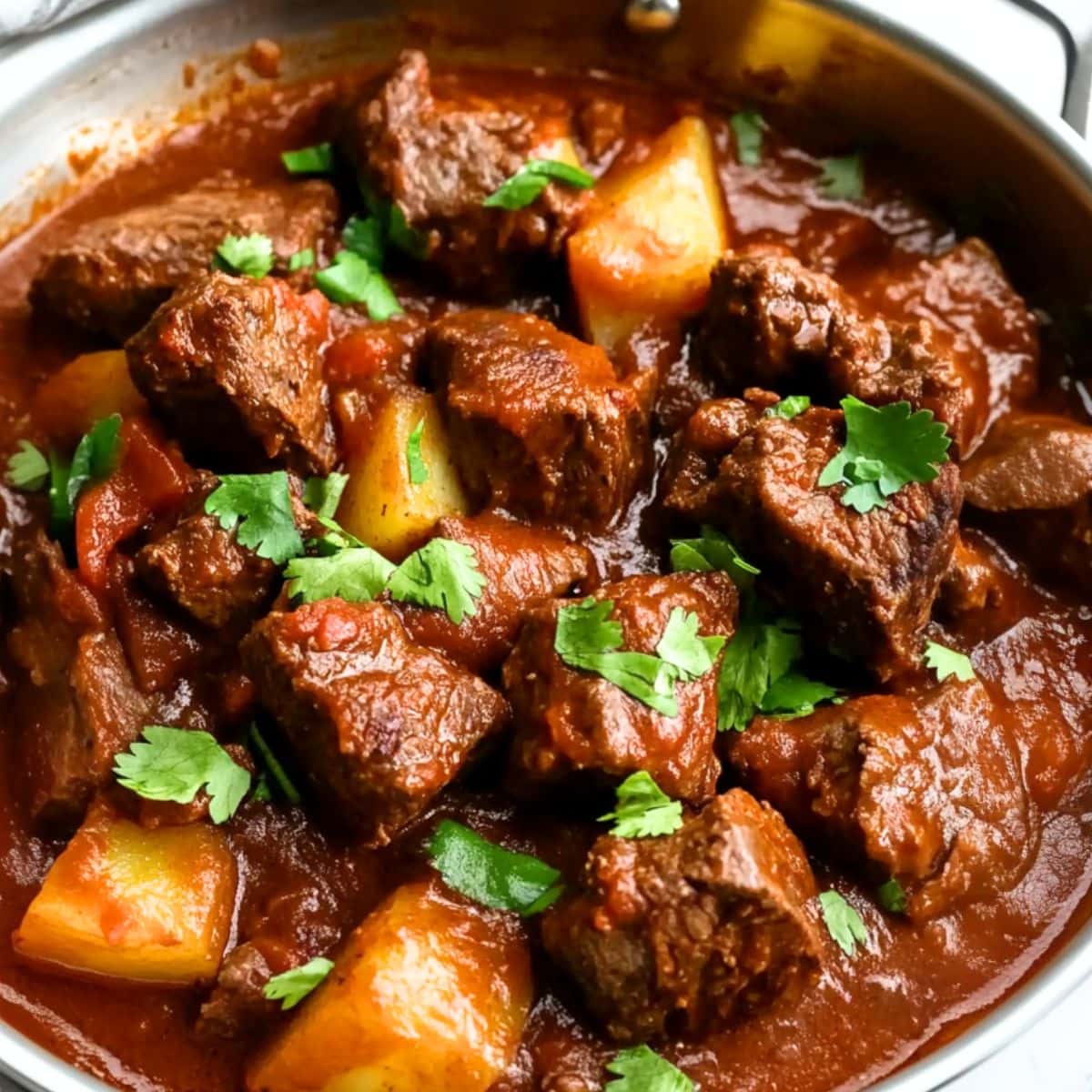 Mexican beef stew with potatoes and savory tomato base sauce in a skillet pan.