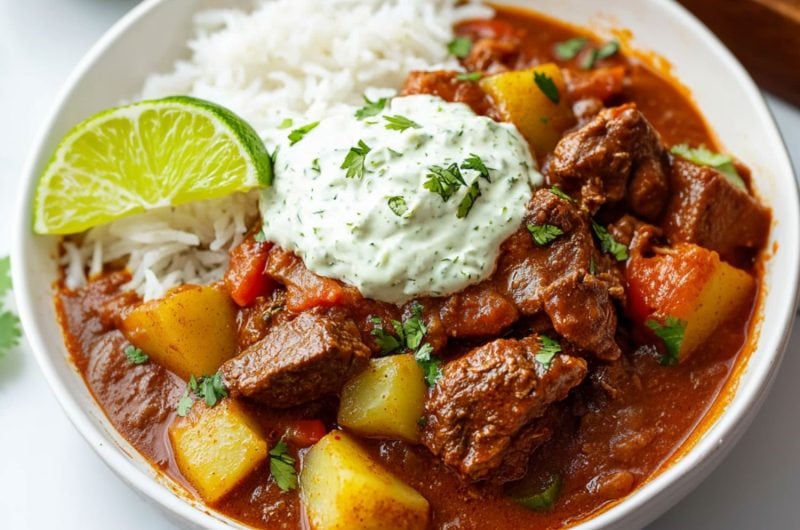 Mexican beef stew served on top of white rice with a dollop of lime crema.