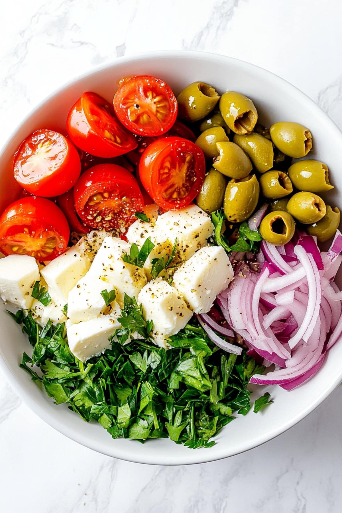 Panzanella Salad Ingredients: Mozzarella, Tomatoes, Red Onions, Green Olives and Herbs in a Bowl.