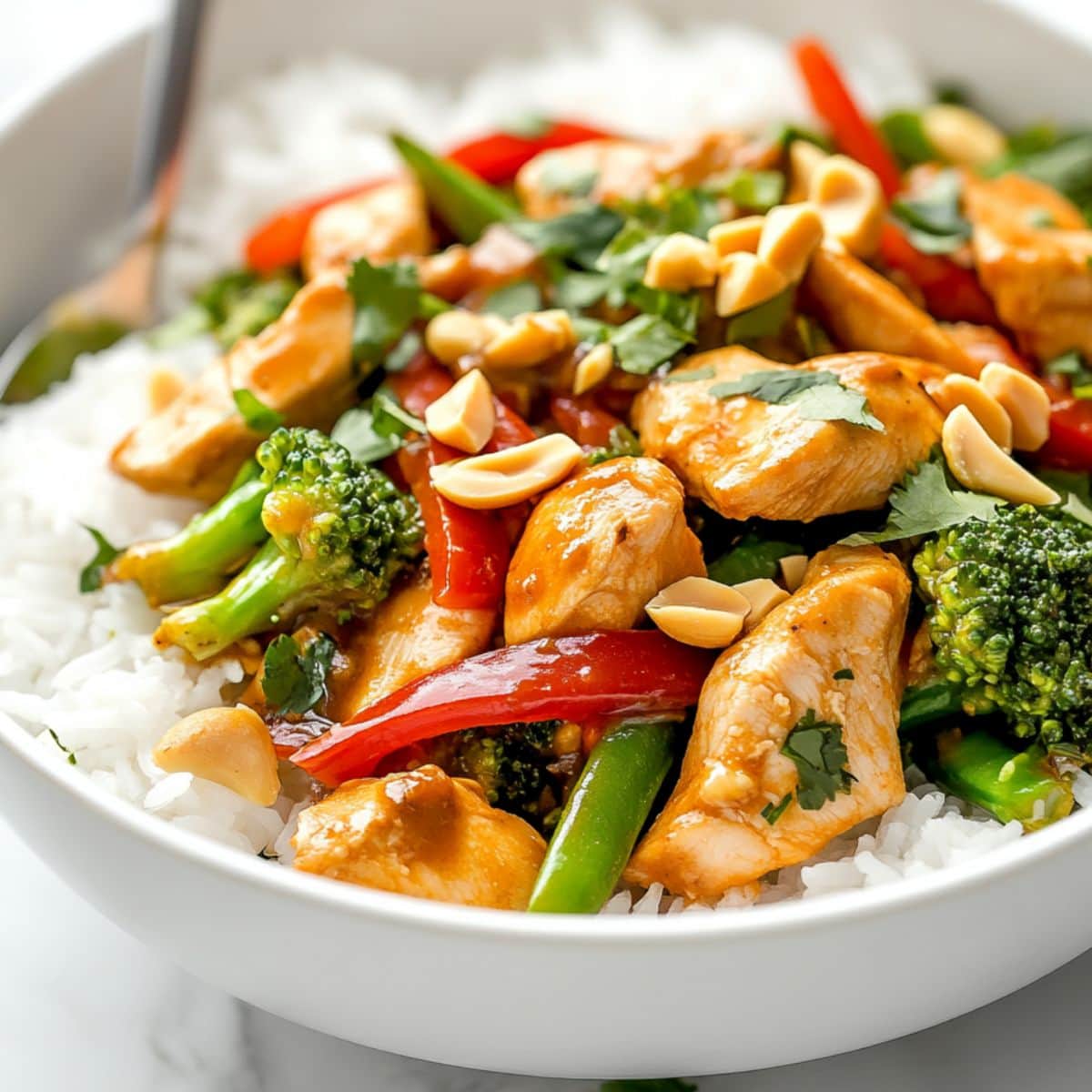 Peanut satay chicken stir fry served on top of white rice in a bowl