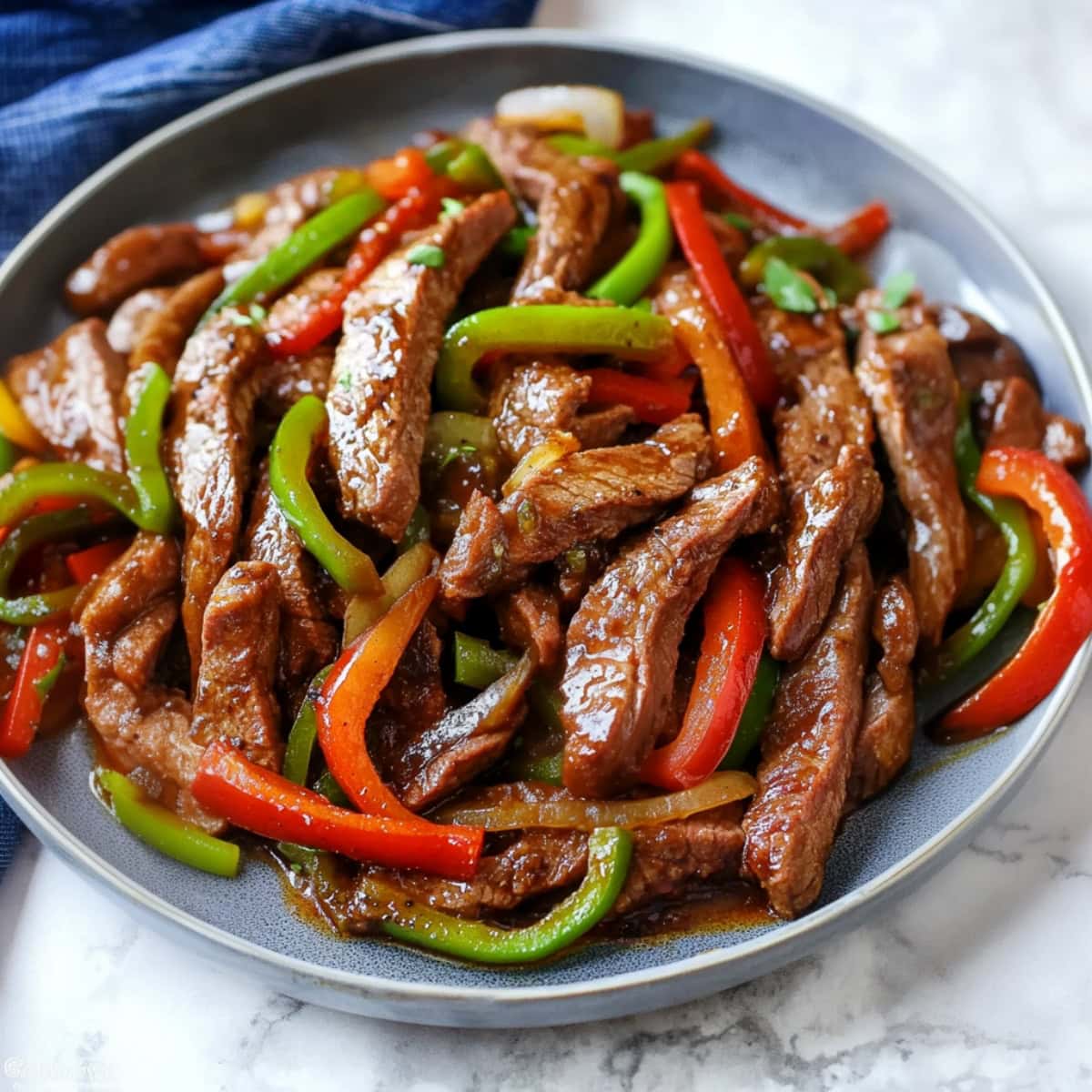 Colorful pepper steak stir fry with vibrant green and red bell peppers with onions on a plate.