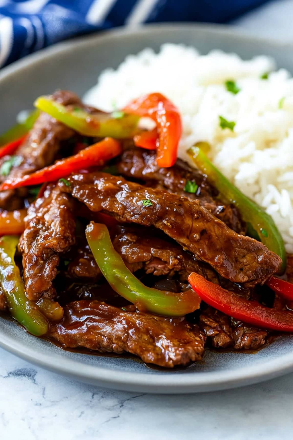 Pepper steak fry served on a plate, with vibrant red and green peppers and a glossy soy-based sauce, served with rice.