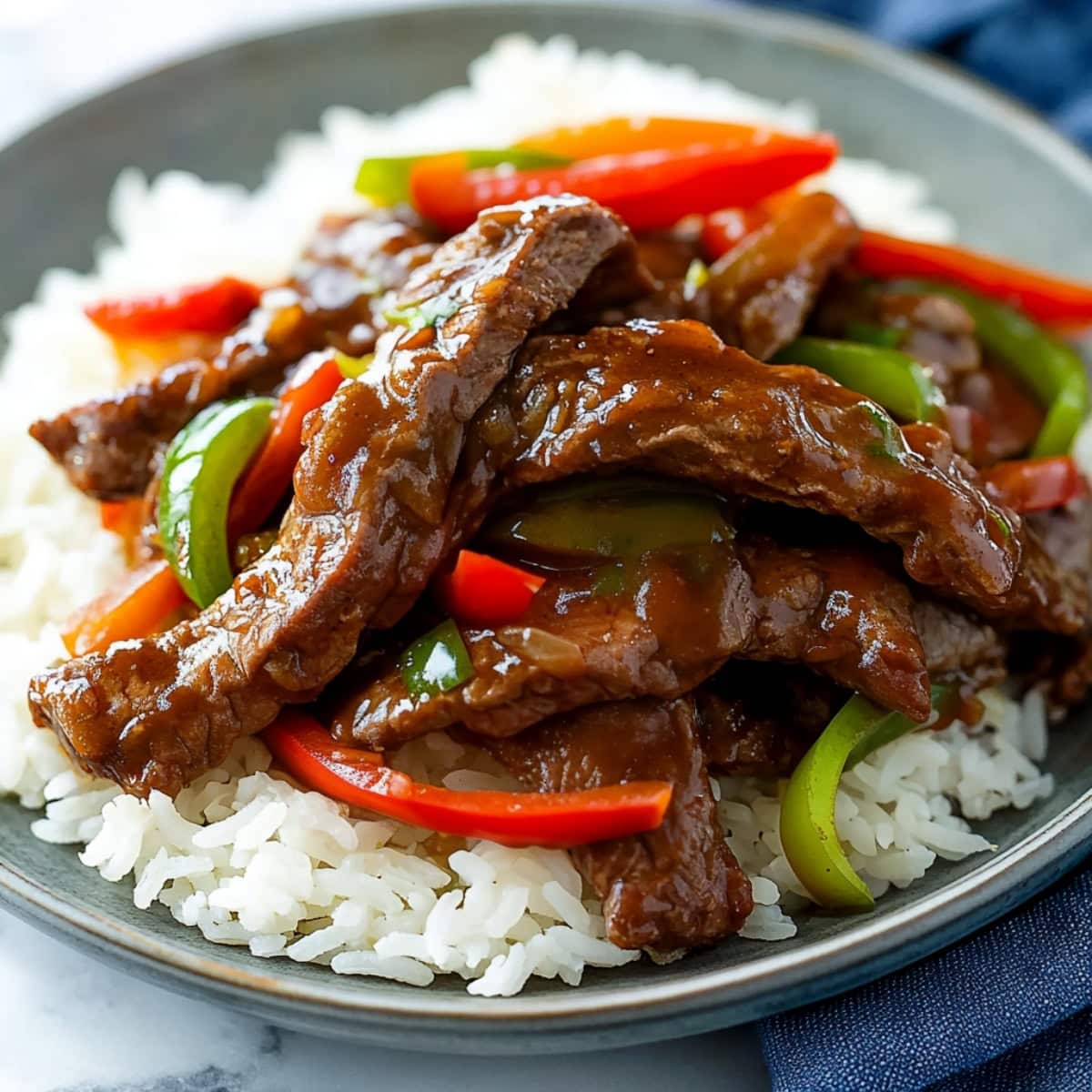 Savory homemade saucy pepper steak stir fry served with rice in a plate.