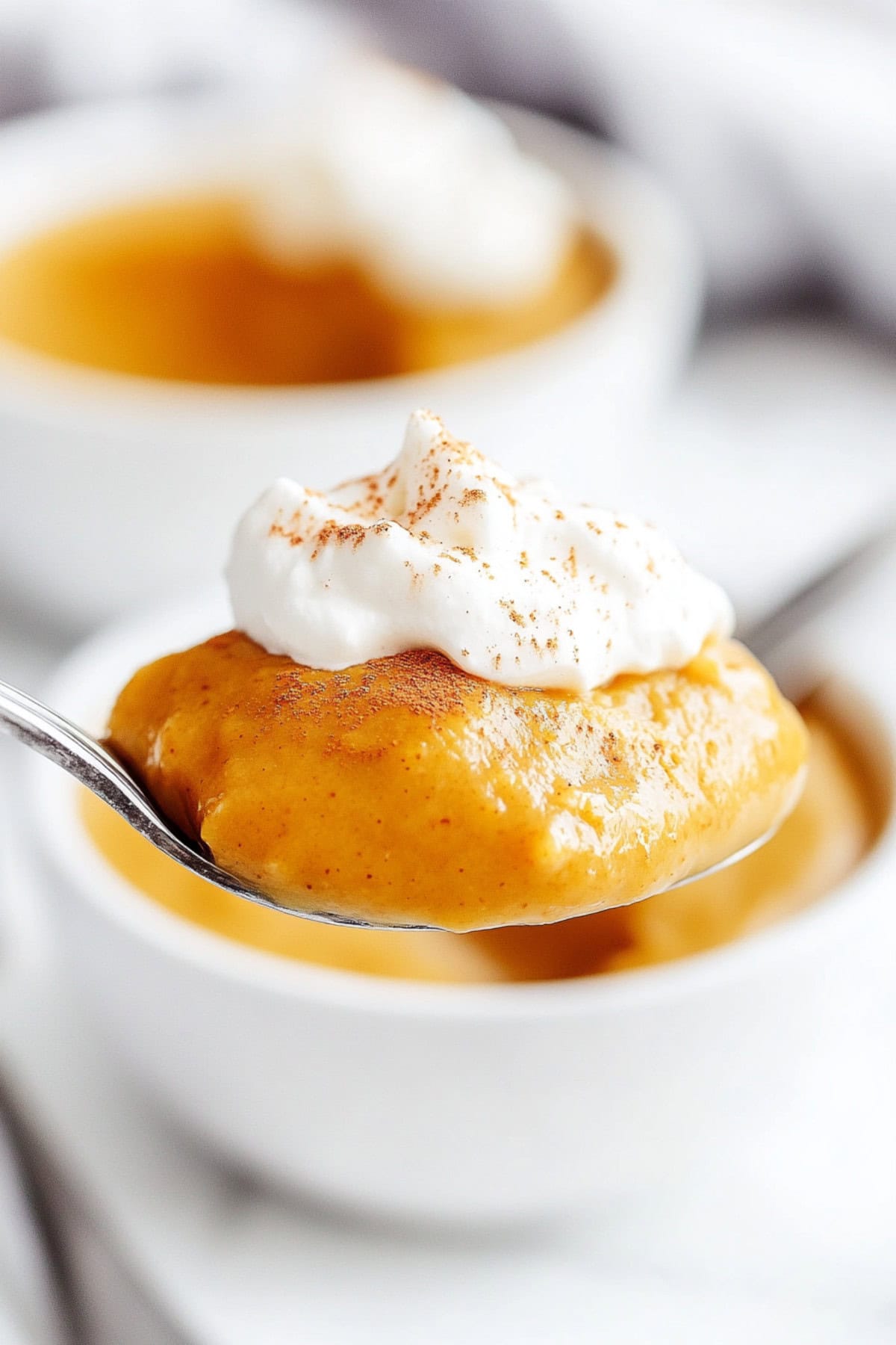 Spoonful of pumpkin pudding garnished with whipped cream, close up