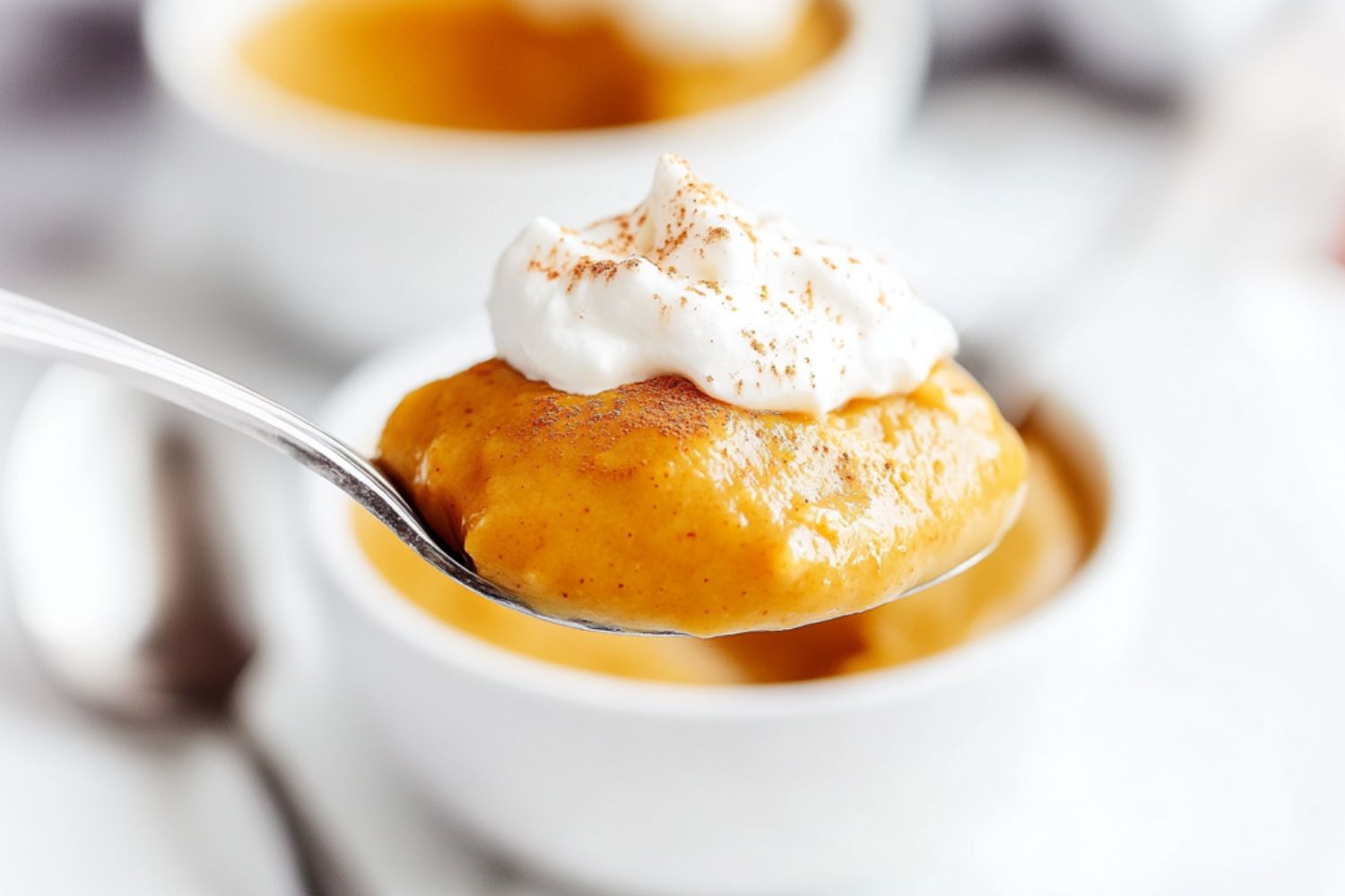 Spoonful scoop of pumpkin pudding with whipped cream.