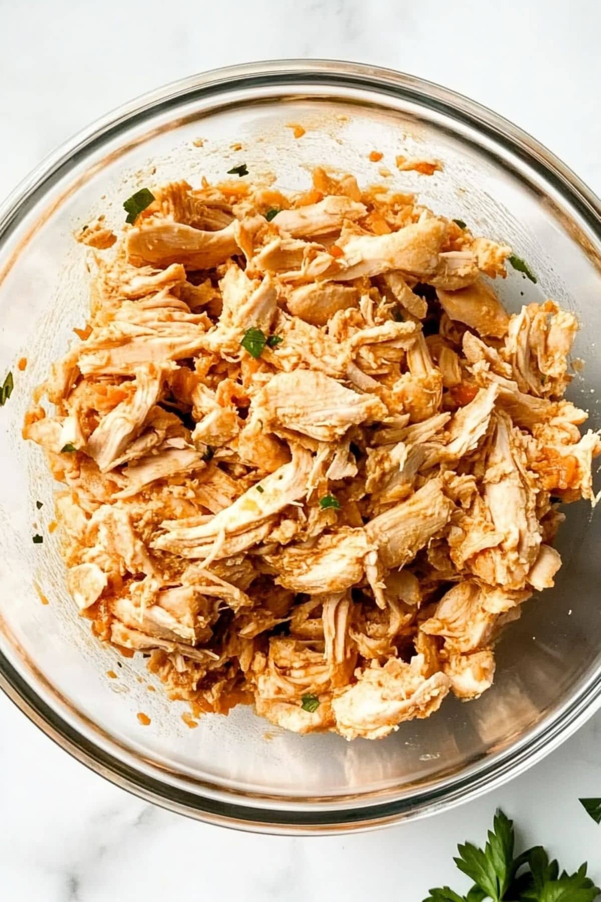 Shredded rotisserie chicken in a glass bowl.