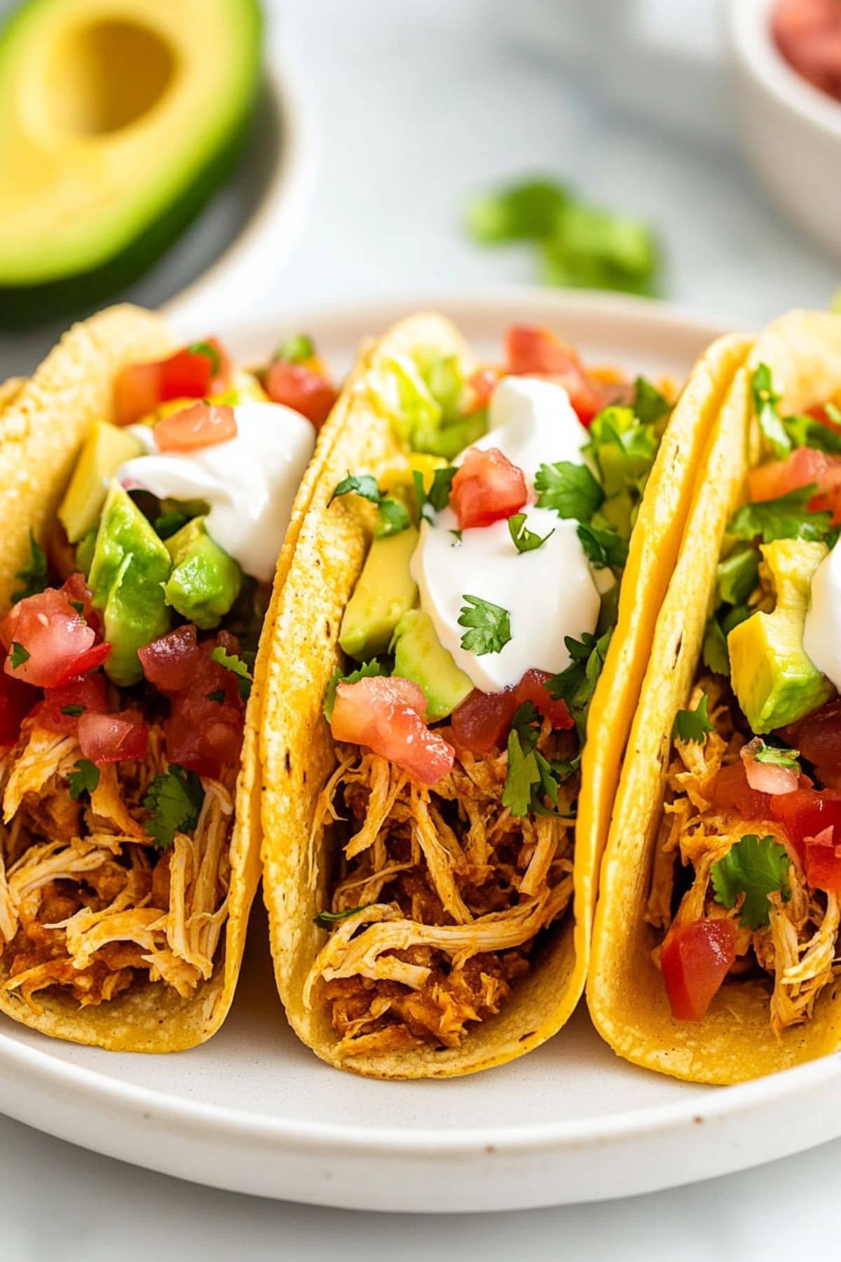 Rotisserie chicken tacos arranged in a white plate.