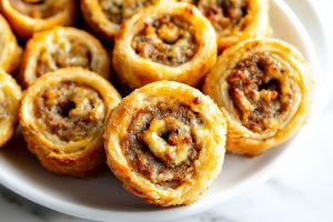 A close-up of pinwheels, showcasing the layers of puff pastry wrapped around seasoned sausage.