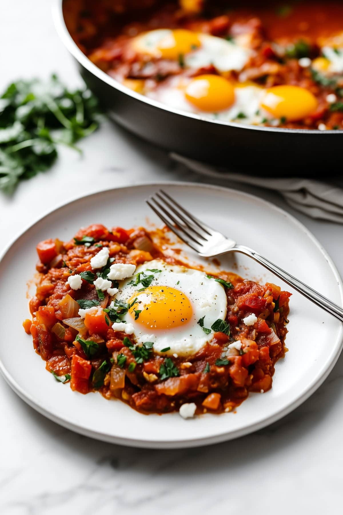 A hearty portion of shakshuka with perfectly a poached egg served on a plate.