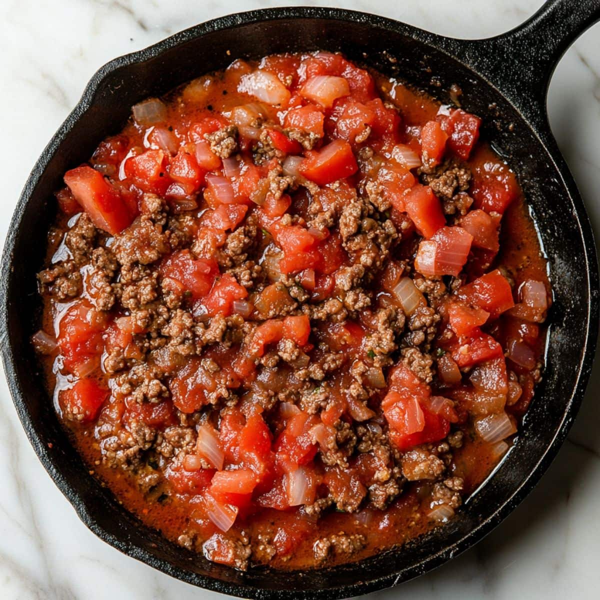 Spaghetti sauce, diced tomatoes, chopped onion, minced garlic, dried basil, dried oregano, salt, and black pepper in a skillet pan.