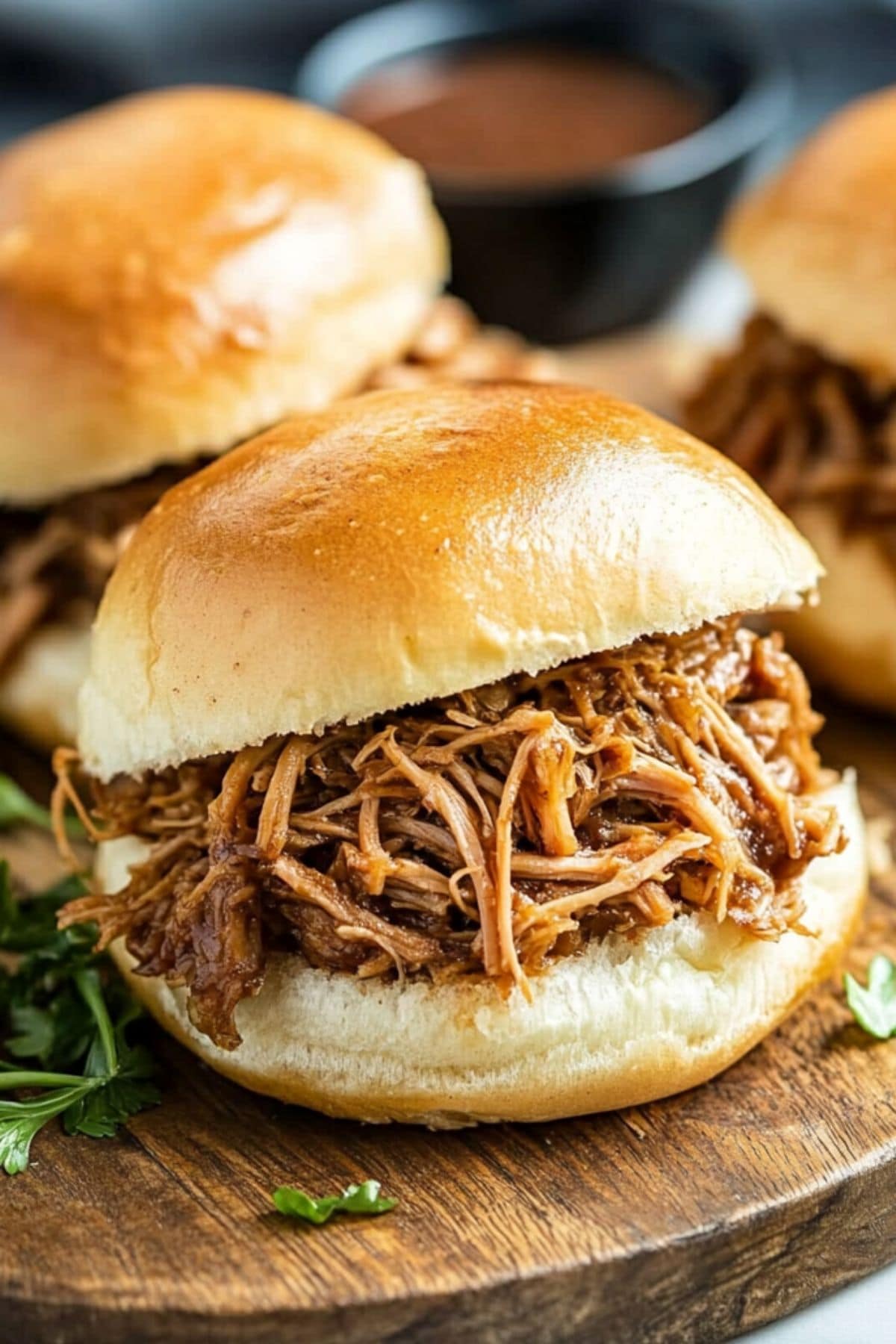 Pulled pork inside buns sitting on a wooden board.