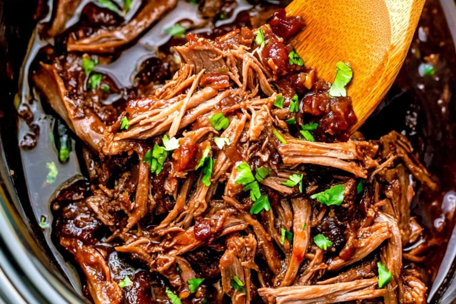 Saucy pulled pork cooked inside a slow cooker.