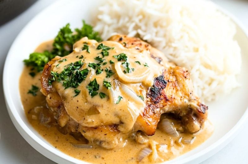 Pan seared chicken with buttery and creamy gravy served with white rice on a plate.