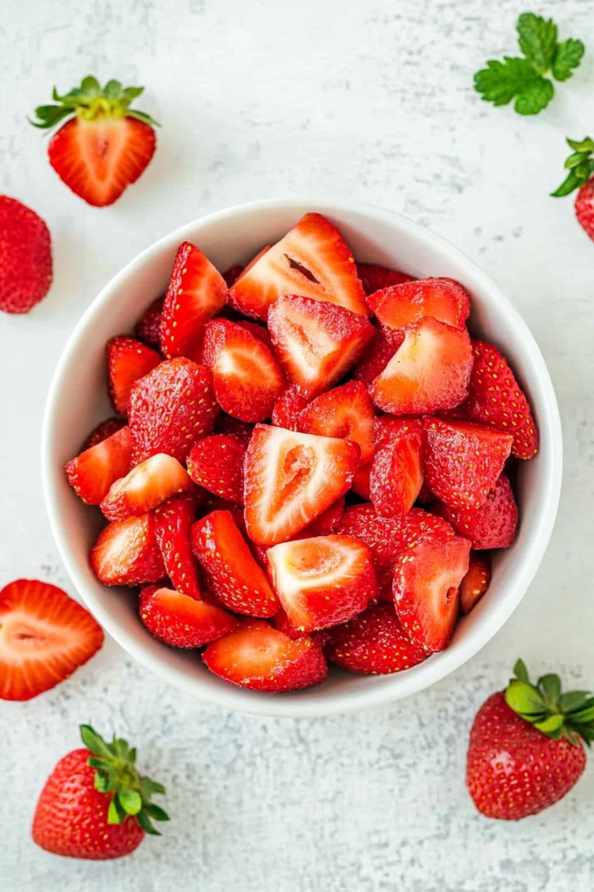 Sliced strawberries in a white bowl.