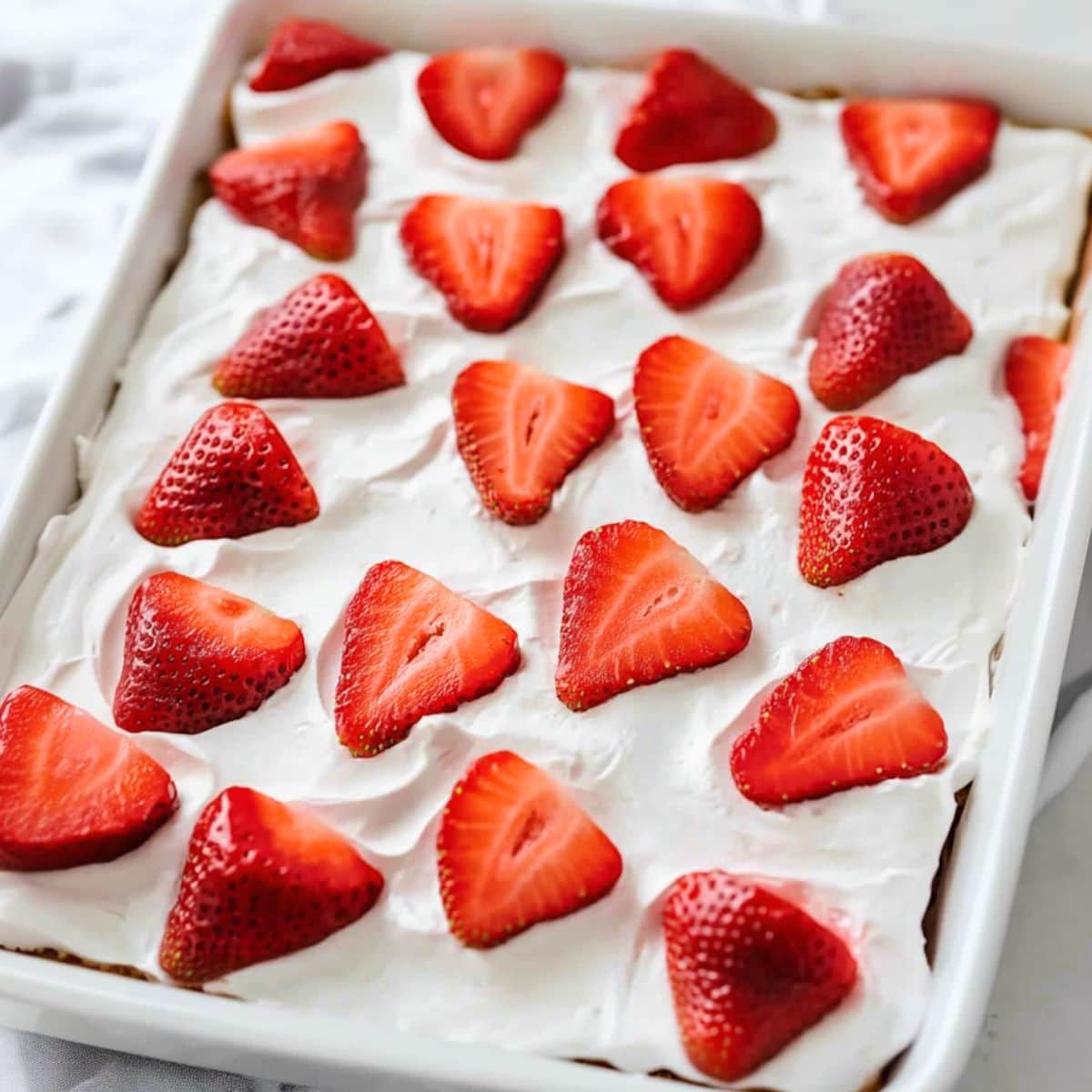 Strawberry icebox cake assembled in a rectangular dish topped with sliced strawberries.