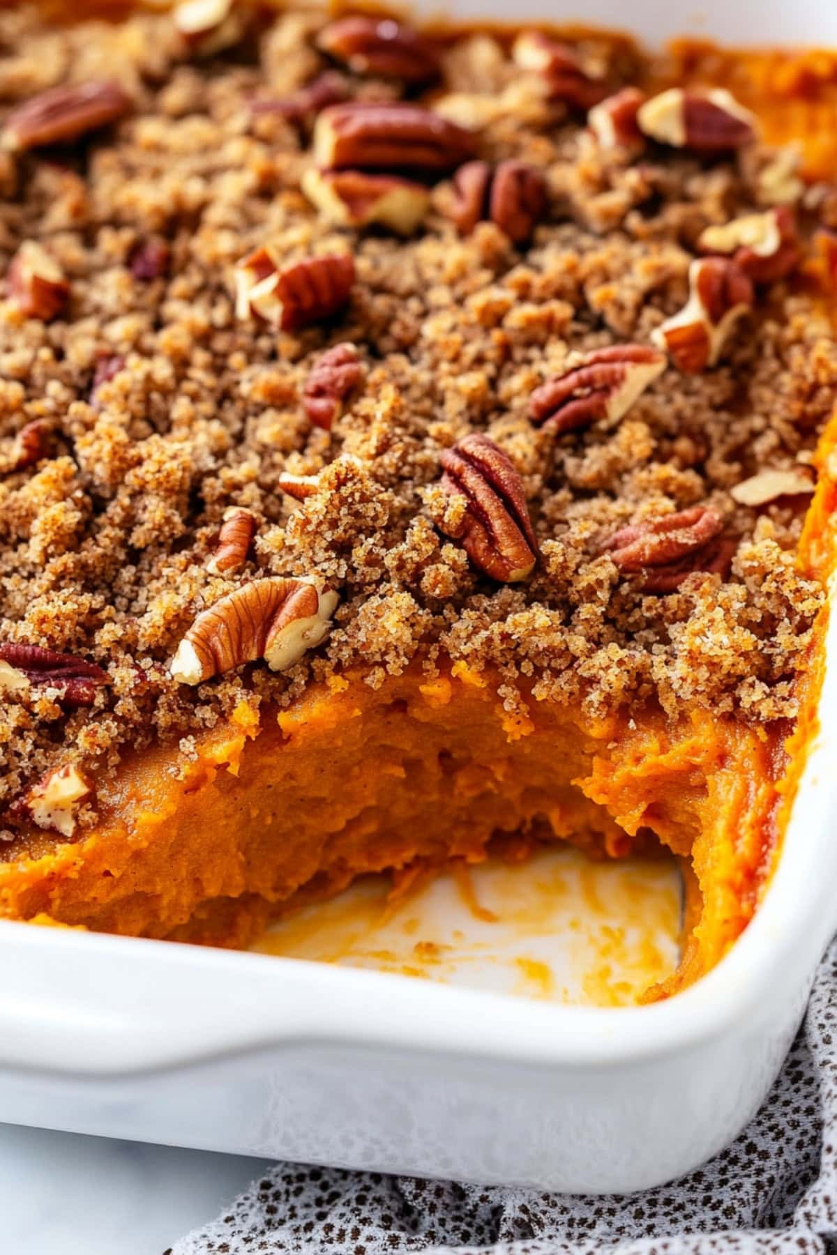 Golden brown sweet potato soufflé with a crisp streusel topping and pecan nuts