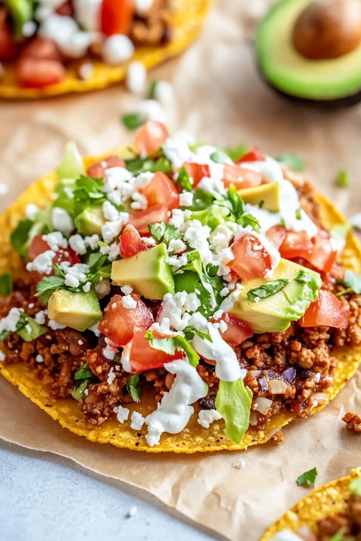 Crispy corn tortillas topped with ground beef, avocados, chopped lettuce, crumbled cheese drizzled with sour cream.