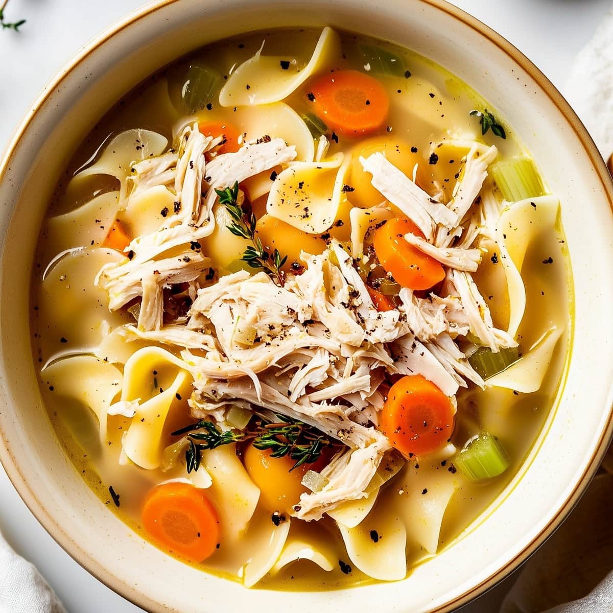 An overhead shot of a warm bowl of turkey noodle soup,