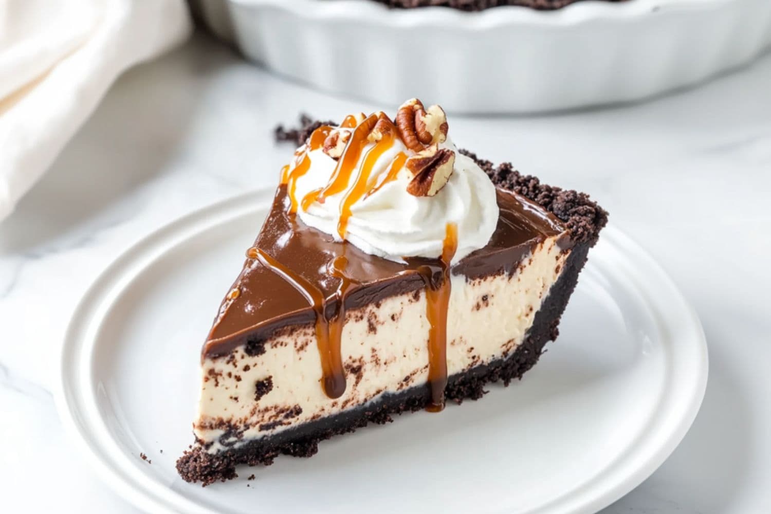 A slice serving of turtle pie with whipped cream, chopped pecans drizzled with caramel; syrup in a white plate.