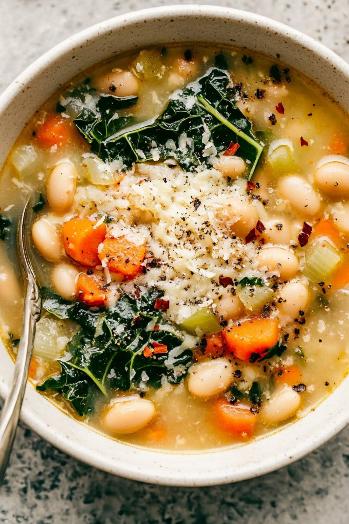 Tuscan white bean soup with kale, carrots, celery and red pepper flakes, topped with grated parmesan cheese.