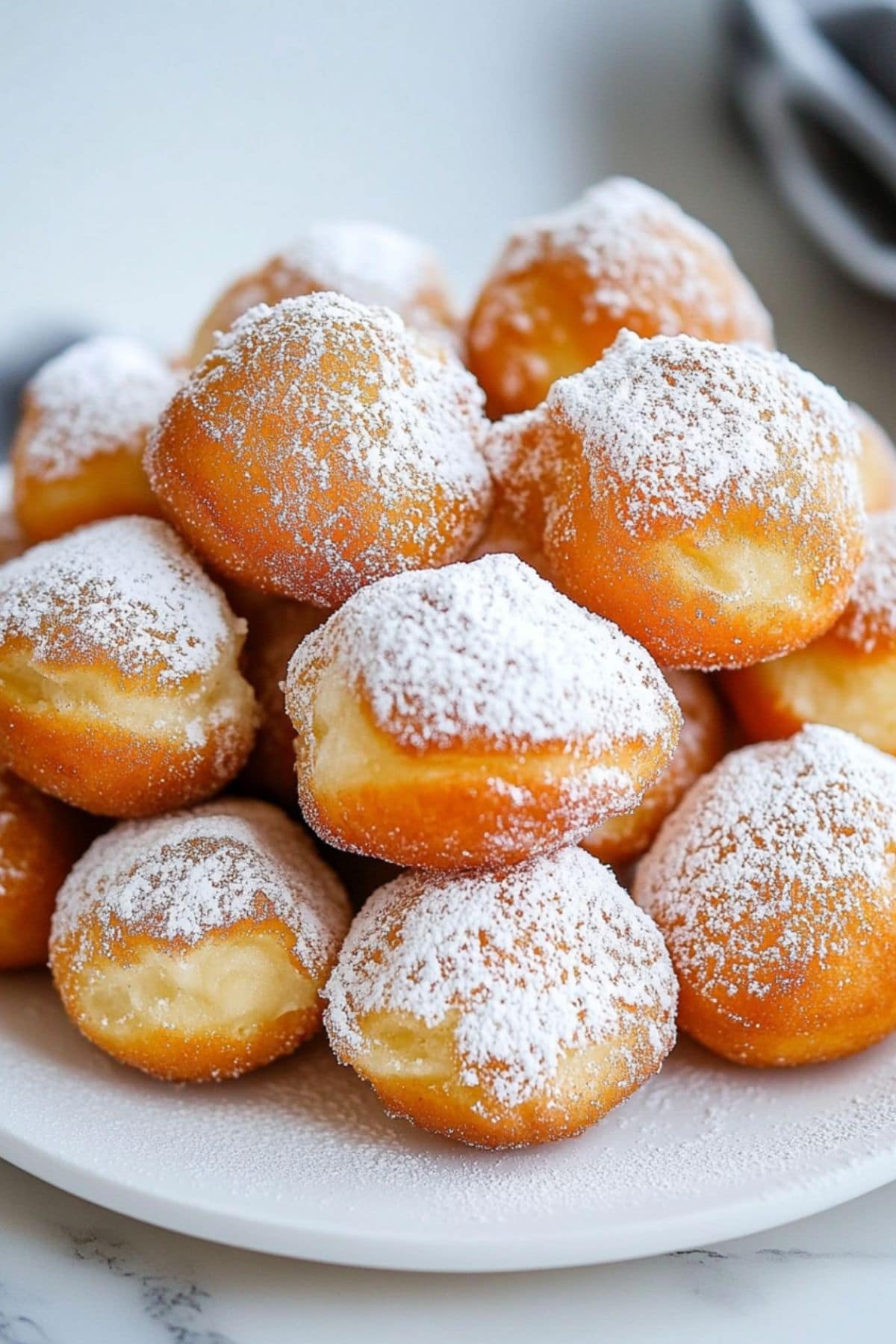 Plate full of warm zeppole donuts dusted with powdered sugar 