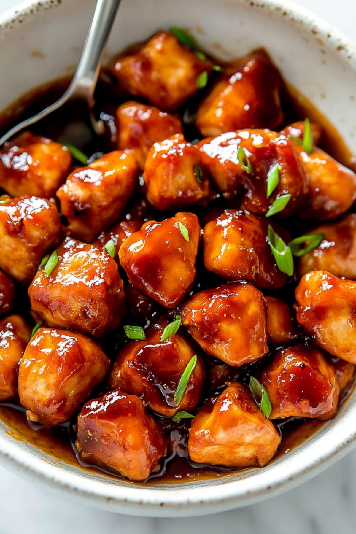 Sticky apricot chicken in a bowl topped with scallion