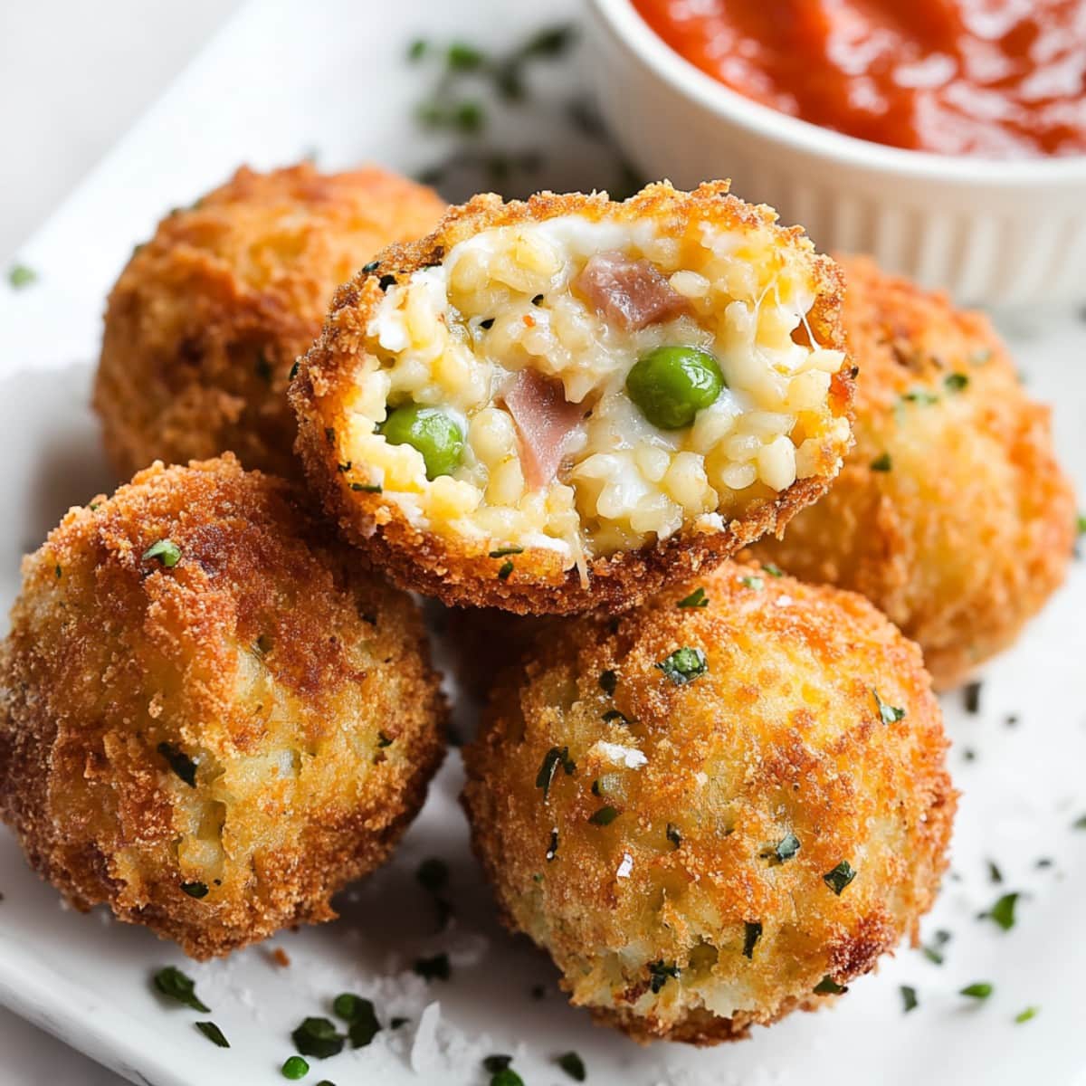 Close-up of crispy arancini with a gooey mozzarella center oozing out.