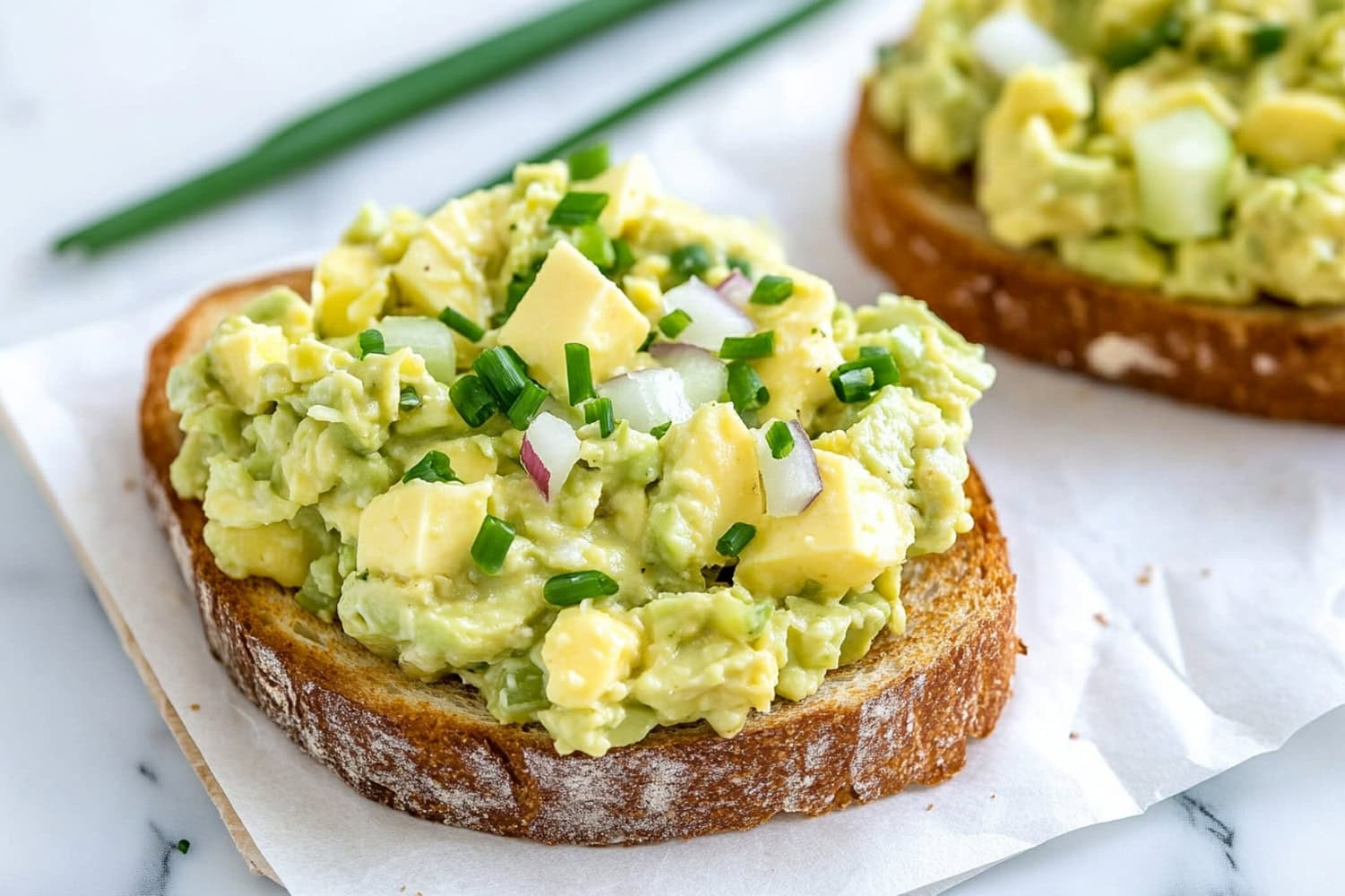 Bread slices served with avocado egg salad on top.