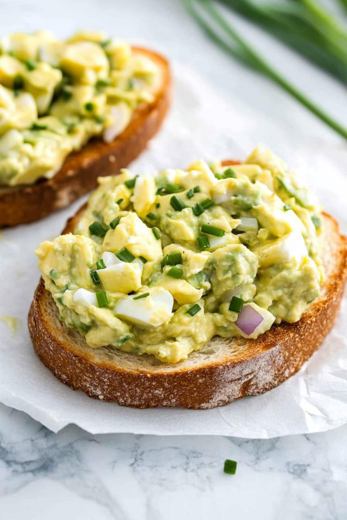 Avocado egg salad served on top of sliced breads.