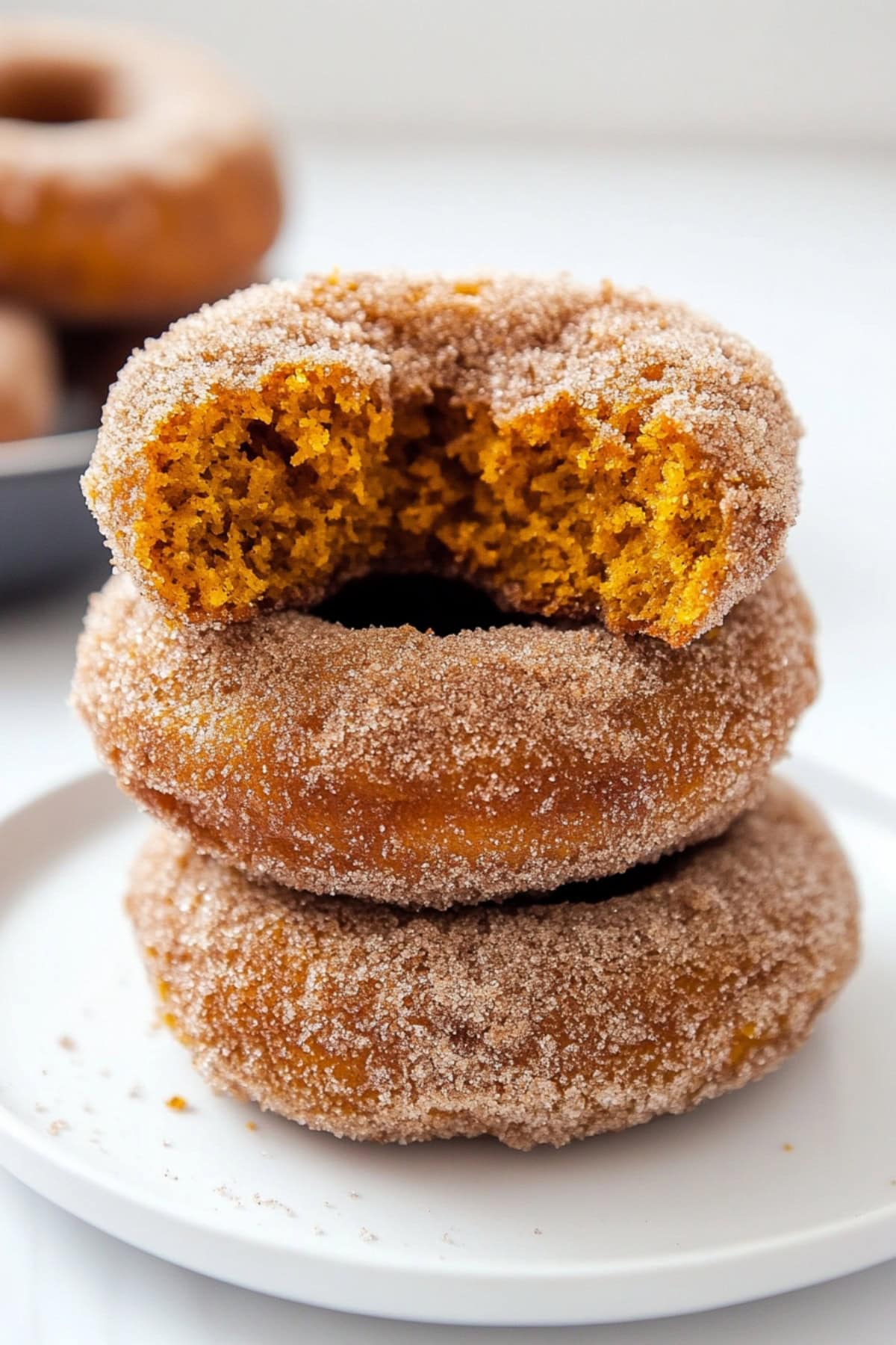 Stack of cinnamon sugar donuts served on a white plate.