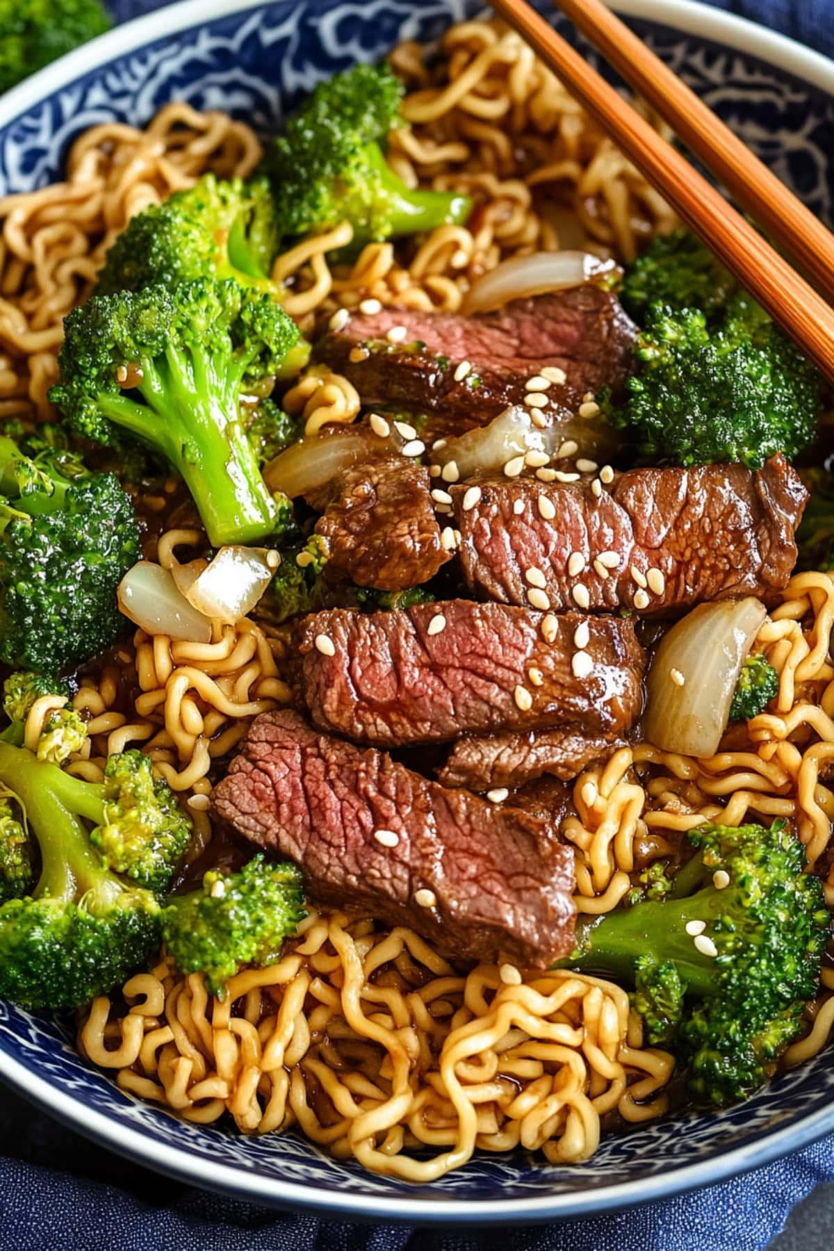 Beef and broccoli stir fried with ramen served in a blue bowl.