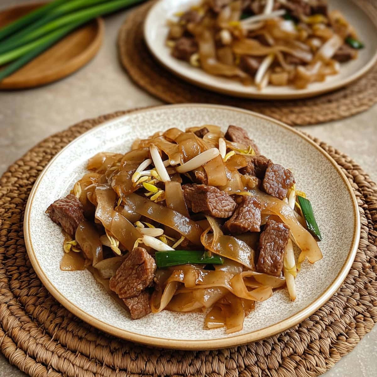 Two servings of beef chow fun in white plates.